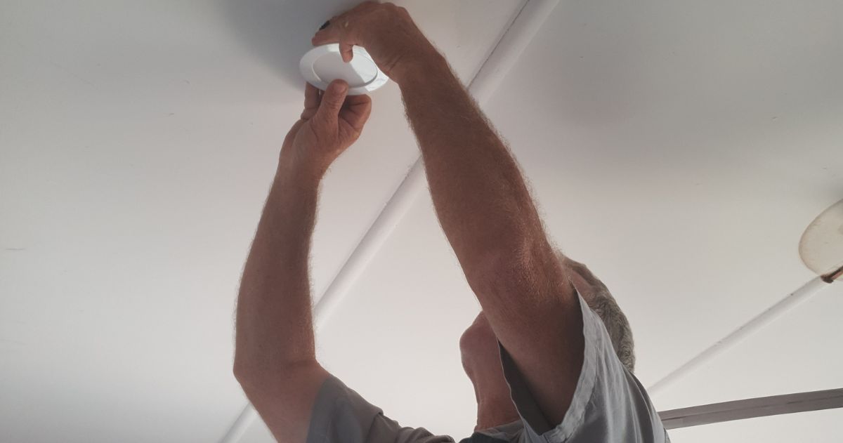 Ian installs an LED into a customer's ceiling.