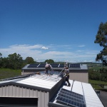 Two men installing solar panels on a roof