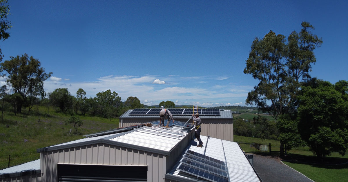 Two men installing solar panels on a roof